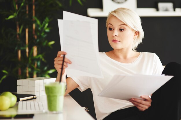 Concentrated businesswoman comparing documents at office