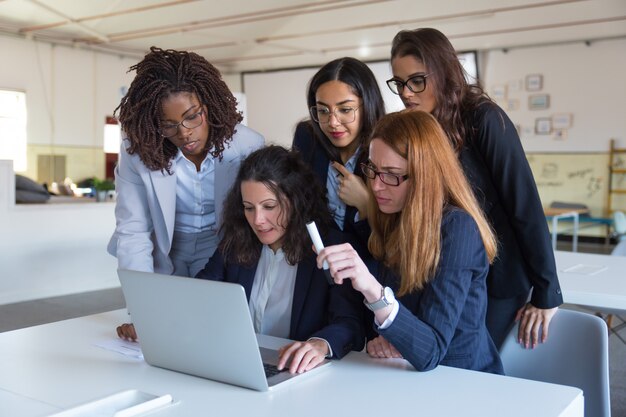 Concentrated businesswomen using laptop in office