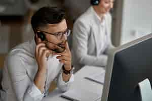 Free photo concentrated call center agent talking with a customer while working in the office