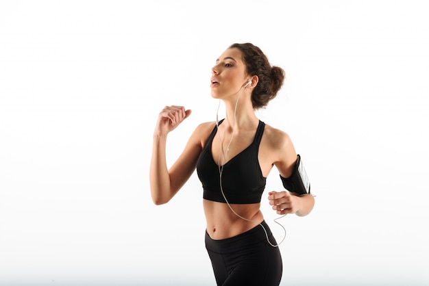 Concentrated curly brunette fitness woman running and listening music