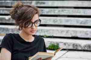 Free photo concentrated female reading book on stairs