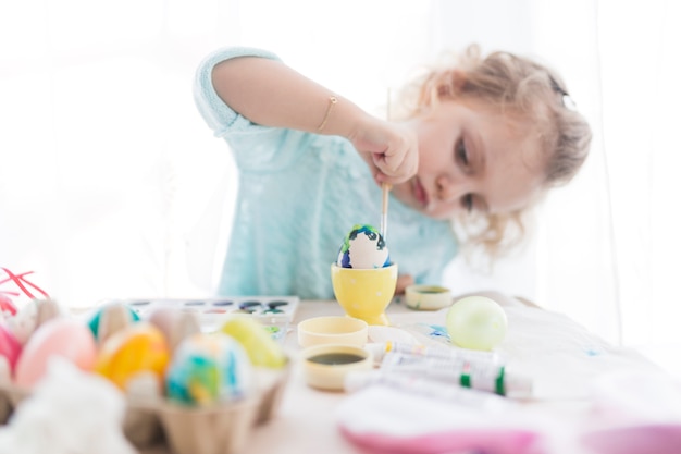 Concentrated girl painting egg