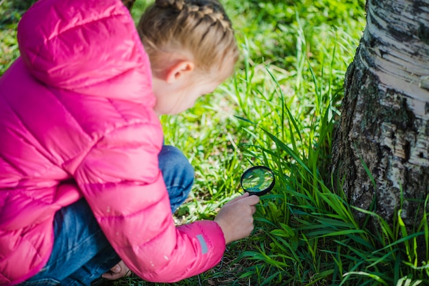 Foto gratuita ragazza concentrata usando una lente d'ingrandimento