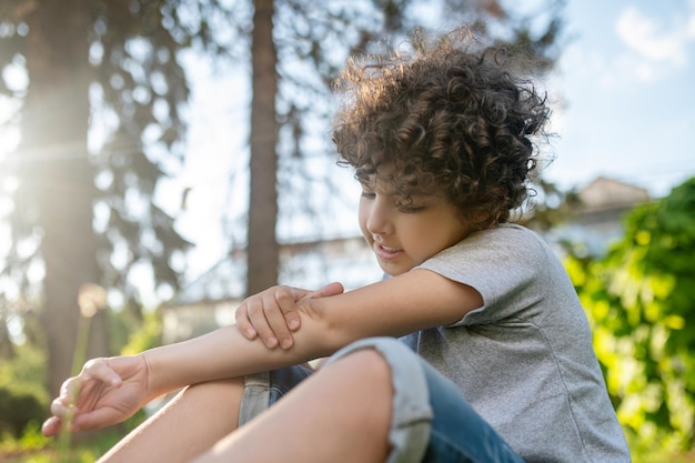 Concentrated kid examining his damaged elbow joint