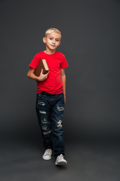 Concentrated little boy child holding book.