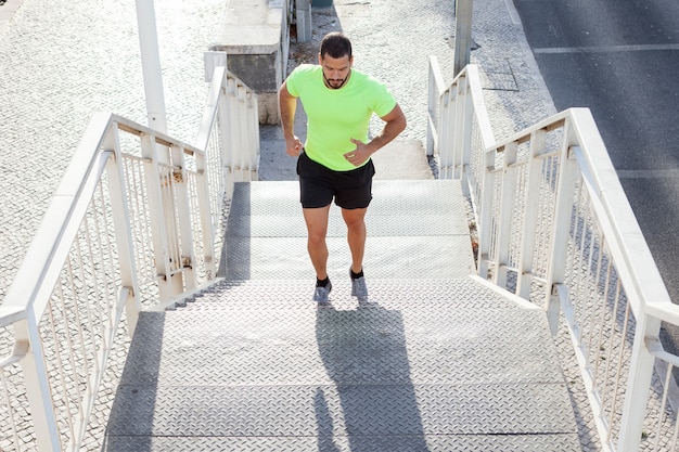 Concentrated male athlete running up stairs