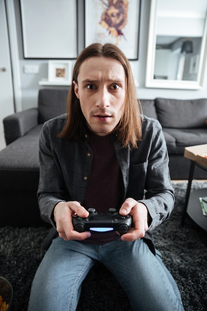 Concentrated man sitting at home indoors play games