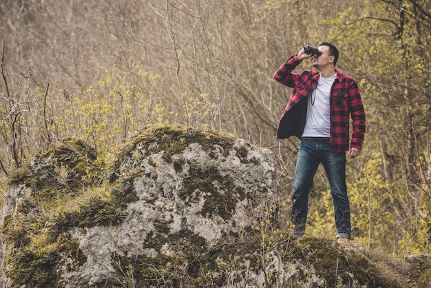 Concentrated man using his binoculars outdoors