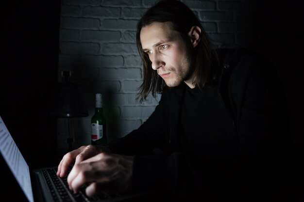 Concentrated man using laptop computer at home indoors