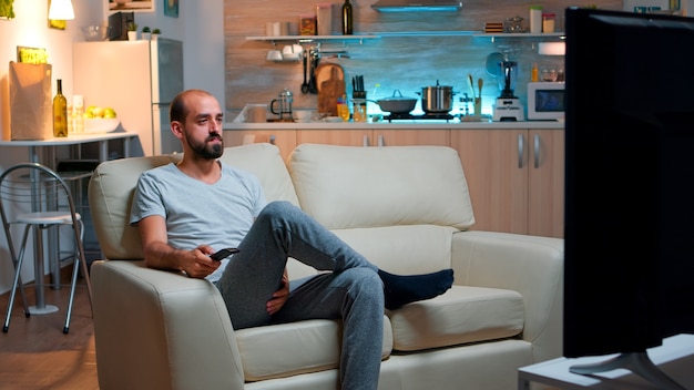 Uomo concentrato con la barba che guarda uno spettacolo di film