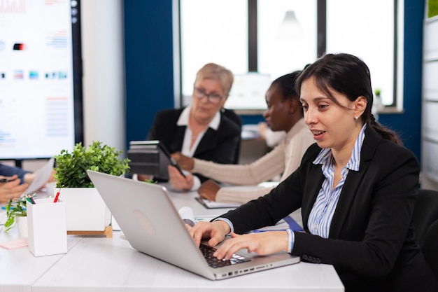 Concentrated manager typing on laptop sitting at desk in start up office