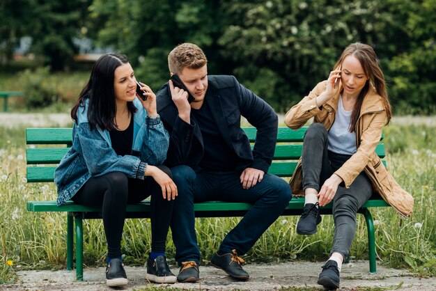 Concentrated people sitting on bench and talking on mobile