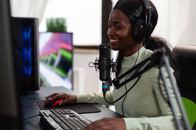 Concentrated pro gamer woman talking into microphone with gamers on live streaming while playing space shooter videogames during online tournament using RGB computer equipment. E sport competition