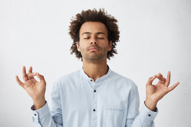 Free photo concentrated relaxed african student with curly hair closing eyes having relaxation