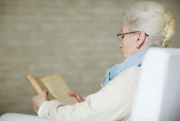 Сконцентрированная пенсионерка читает старую книгу