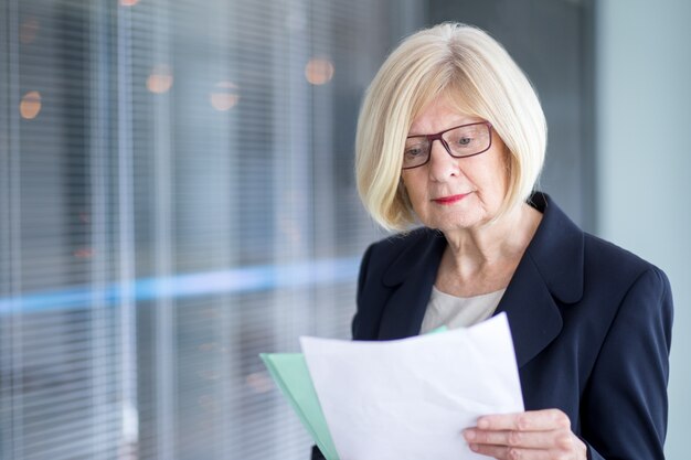 Concentrated senior businesswoman reading papers