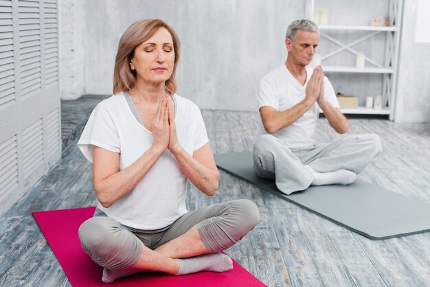 Concentrated senior couple performing yoga at home