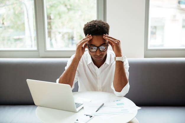 Concentrated serious young african man sitting coworking