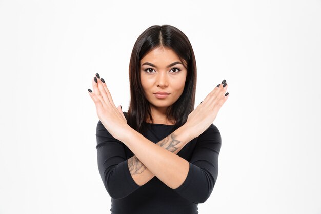 Concentrated serious young asian lady showing stop gesture