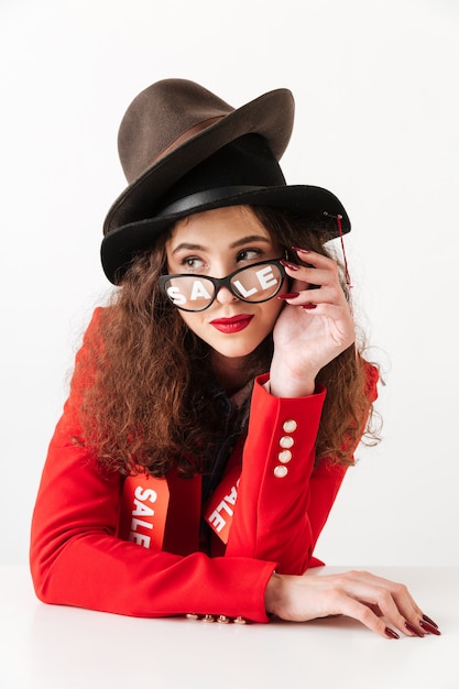 Concentrated serious young caucasian lady wearing hats by sale.