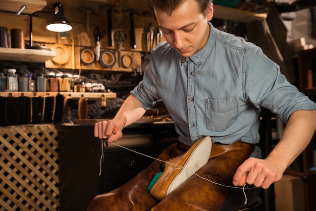 Concentrated shoemaker in workshop making shoes