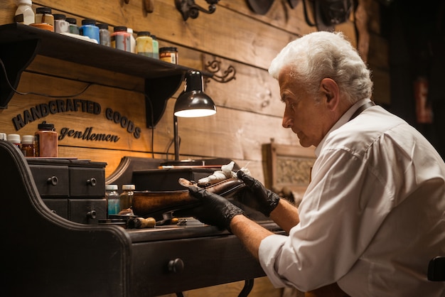 Concentrated shoemaker in workshop making shoes