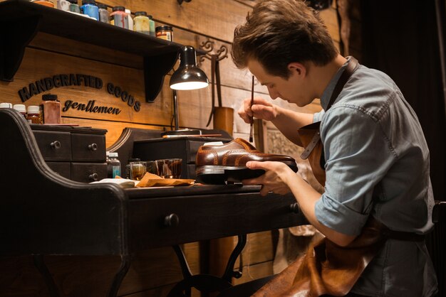 Concentrated shoemaker in workshop making shoes