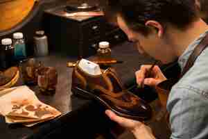 Free photo concentrated shoemaker in workshop making shoes