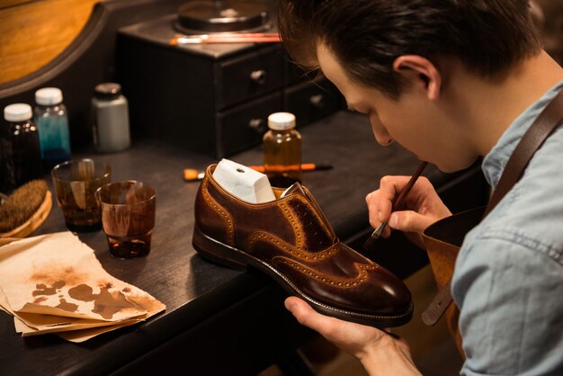 Concentrated shoemaker in workshop making shoes