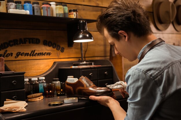 Concentrated shoemaker in workshop making shoes