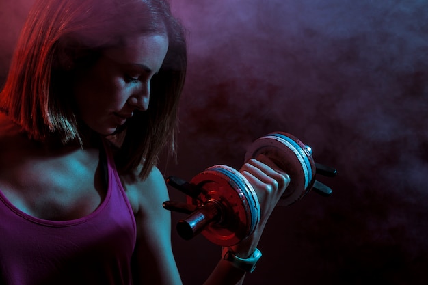 Concentrated sportswoman with heavy dumbbell