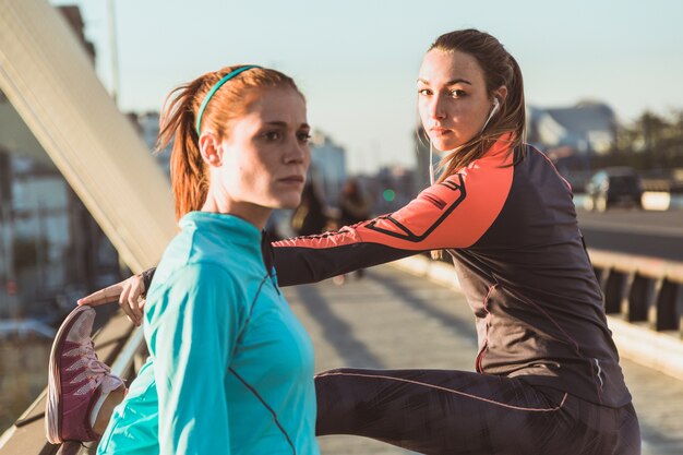 Concentrated sportswomen stretching before running