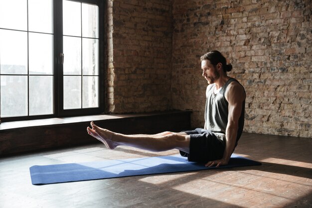Concentrated strong sportsman in gym make yoga sport exercises