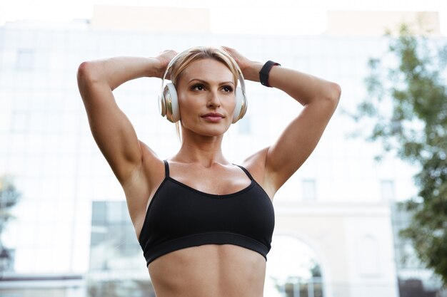 Concentrated strong young sports woman listening music