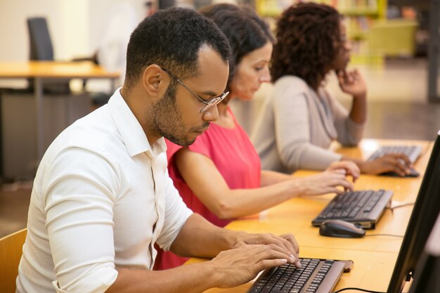 Concentrated students working with computers at library