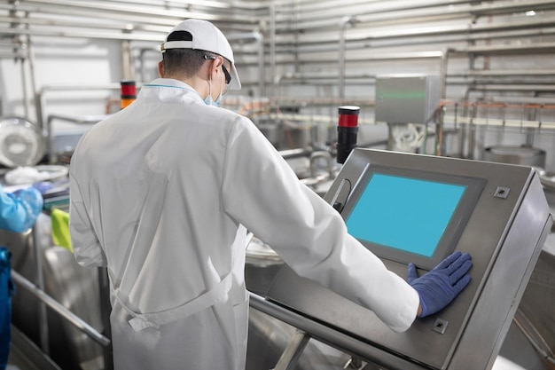 유제품 공장의 생산 부서에 서 있는 동안 디지털 태블릿의 도움으로 필요한 메모를 하는 집중된 기술자 검사관이 치즈 공장에서 제어를 수행합니다.