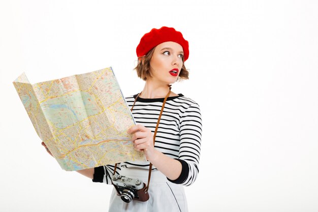 Сконцентрированная туристическая женщина с камерой держа карту.