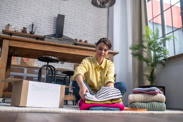 Foto gratuita donna tranquilla concentrata che imballa capi di abbigliamento