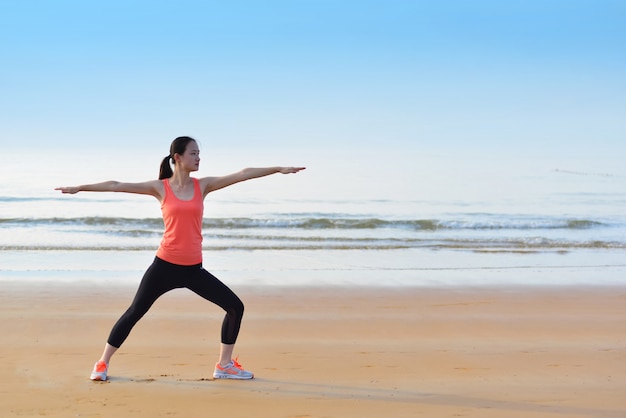 Concentrated woman exercising on the beach