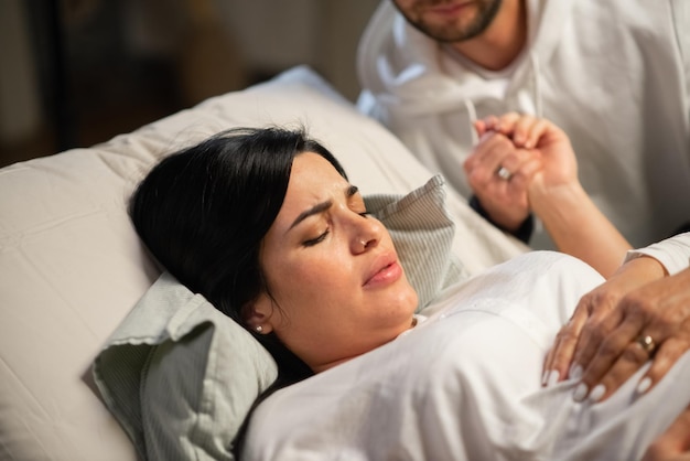 Foto gratuita donna concentrata che partorisce a casa. donna con piercing al naso sdraiato, sentendo contrazioni durante il parto. gravidanza, concetto di nascita in casa