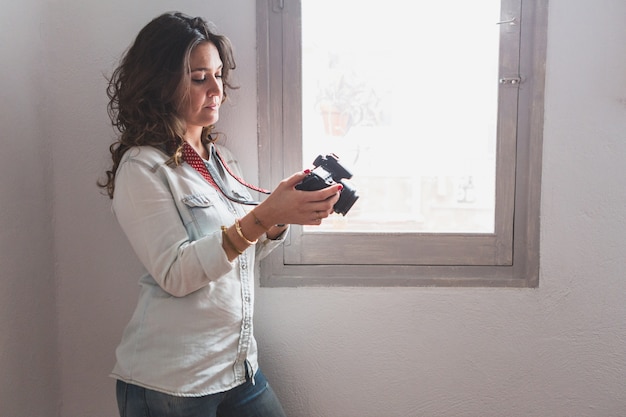 Концентрированные женщина смотрит фотографии рядом с окном