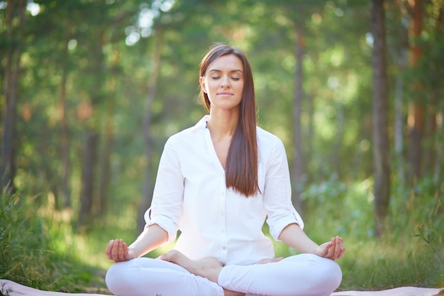 Concentrated woman meditating in nature