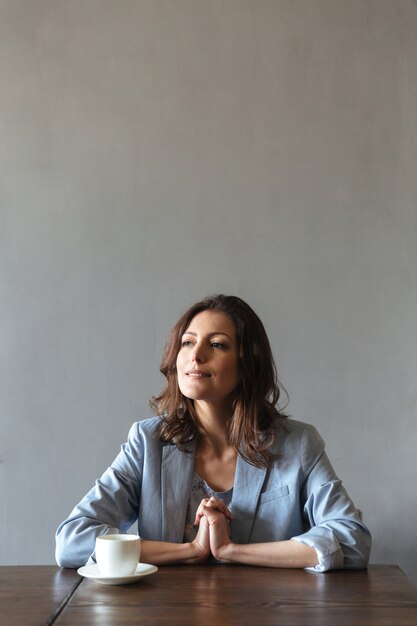 Concentrated woman sitting indoors near cup of coffee