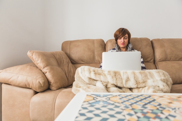 Concentrated woman using her laptop on the couch