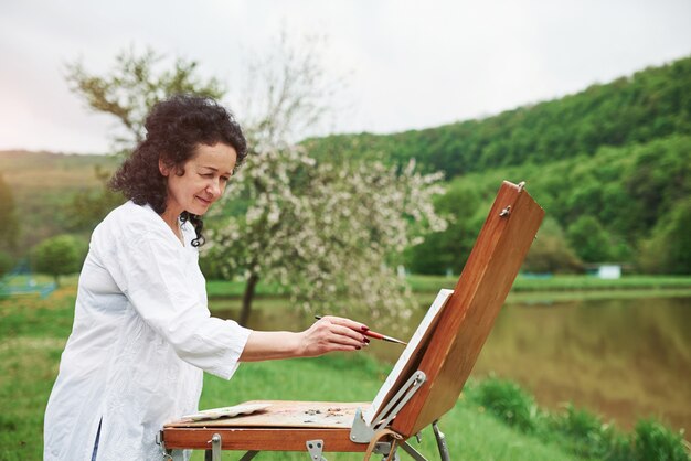 Concentrated at work. Portrait of mature painter with black curly hair in the park outdoors