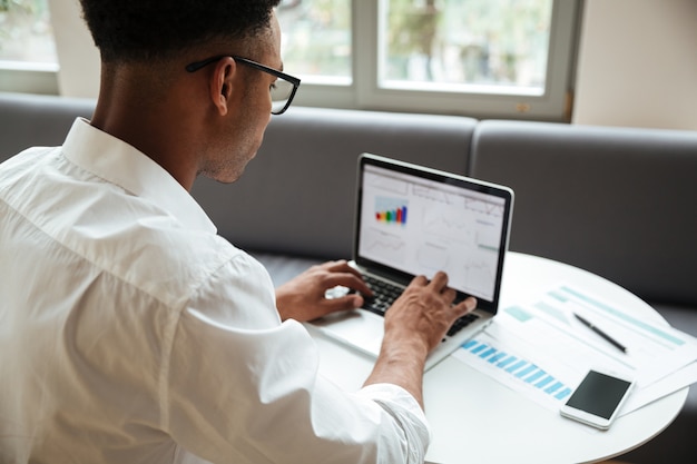 Free photo concentrated young african man sitting coworking