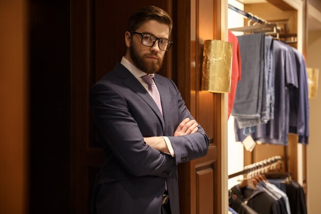 Концентрированный молодой бородатый бизнесмен, стоя в помещении