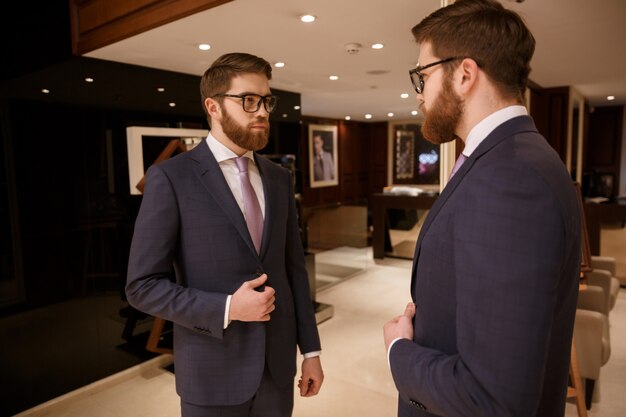 Концентрированный молодой бородатый бизнесмен, стоя в помещении