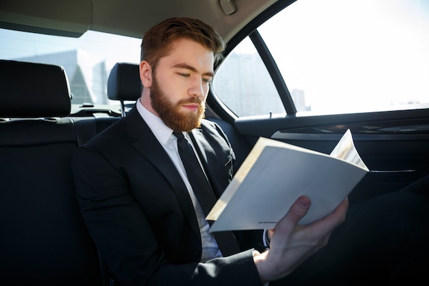 Concentrated young businessman analyzing documents while traveling