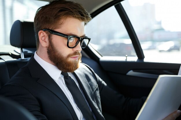 Concentrated young businessman analyzing documents while traveling